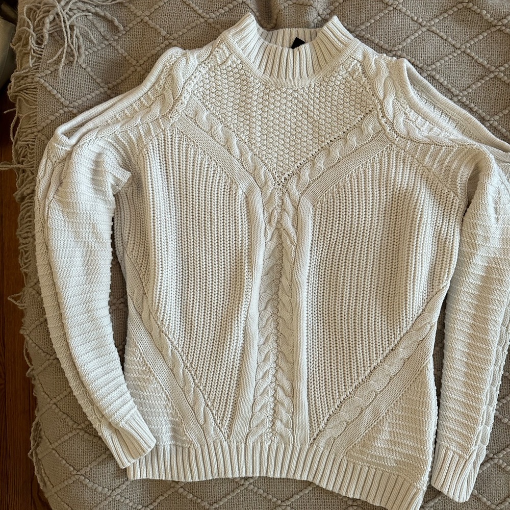 Cream sweater with cutout shoulders.